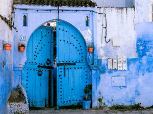 A blue building with an arched blue wooden door.
