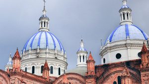 Twin cathedral domes adorned in blue, with an orange brick building in the foreground.