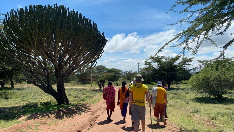 A small group in Kenya walks along a dirt road.