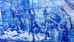Azulejos azules que representan a soldados con casco con hachas de batalla, espadas y escudos.