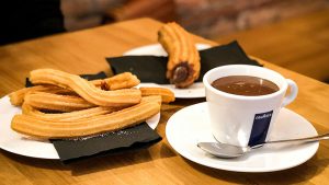 Churros and hot chocolate on a cafe table.