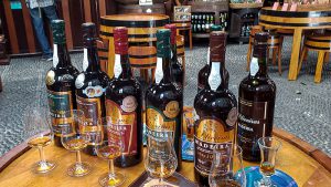 A row of six bottles of Madeira wine and tasting glasses in front of them
