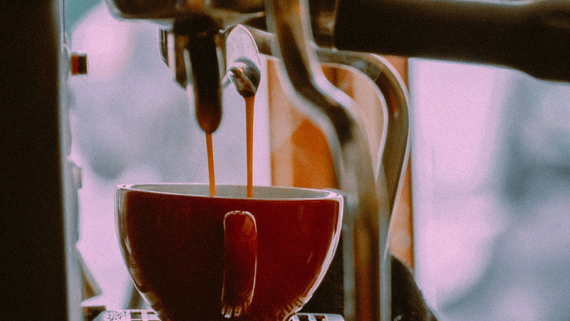 Closeup of espresso dripping into a mug.