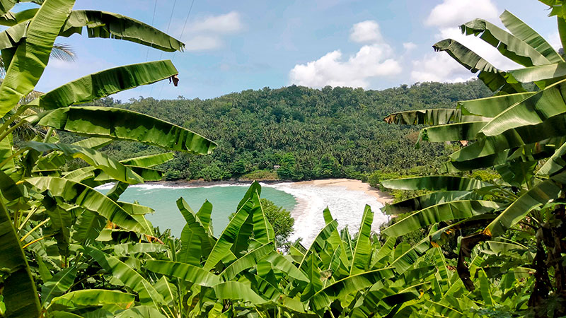 Beautiful inlet on Sao Tome, surrounded by white beach and green vegetation.