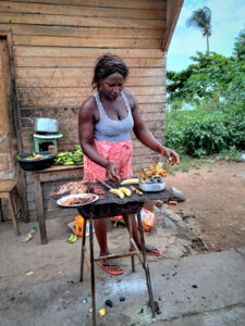 A woman grills fish outdoors.