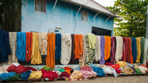 A row of colorful cloths hangs at a market.