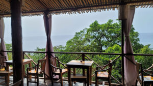 Mucumbi restaurant's quaint wooden tables and chairs on a deck overlooking the sea.