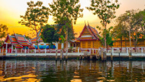 View of traditional Thai architecture from a boat on a river.